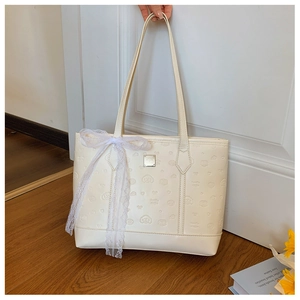 Detail of cream white tote bag featuring cartoon dog embossing and lace bow accessory