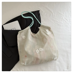 Macro view of organza tote with 3D floral embroidery and blue checkered straps