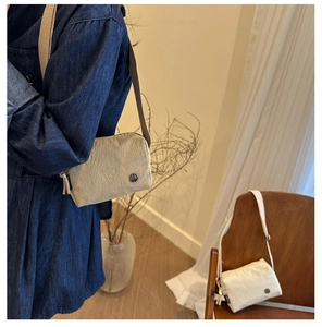 Detail of light khaki nylon crossbody bag with adjustable strap and crinkle texture