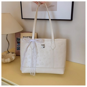 Detailed view of cream leather tote with embossed patterns and large lace bow accent