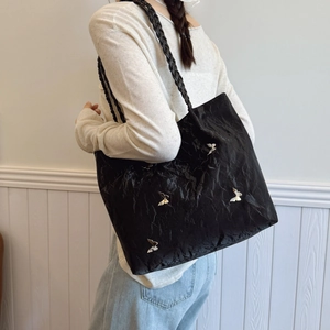 Minimalist black wrinkled tote bag with silver butterfly charms and woven straps