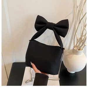 Close-up of black bow-knot canvas handbag with metal chain strap and matte finish