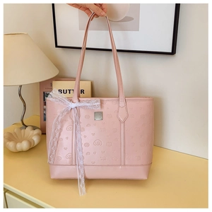 Detail of light pink tote bag with embossed cartoon bear patterns and white lace bow