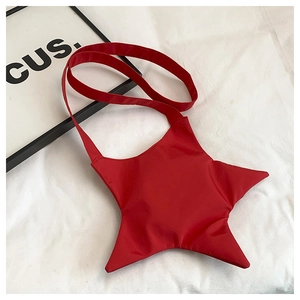 Detailed view of red star-shaped crossbody bag with matching shoulder strap on white fabric