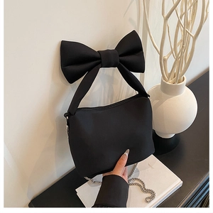 Close-up of black bow-shaped handle and silver chain strap on fabric handbag