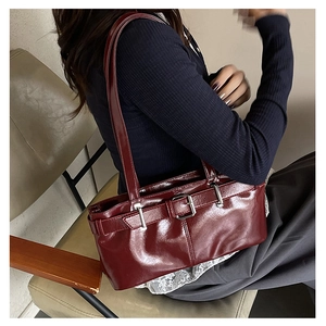 Close-up of deep red glossy patent leather handbag with metallic buckle and slim straps