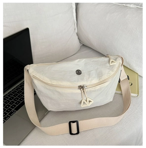 Detail of creamy white nylon crescent crossbody bag with metal logo on a soft background