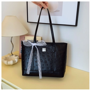 Macro shot of black embossed heart leather tote bag with white lace ribbon detail