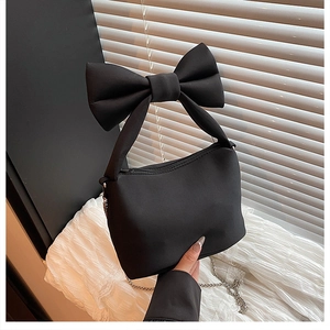 Detail shot of black bow handbag with silver chain strap and matte texture finish