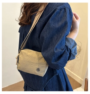 Close-up of khaki nylon crossbody bag with textured fabric and branded side woven label