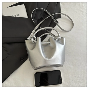 Detailed size reference of silver pleated bucket bag next to a smartphone on white background