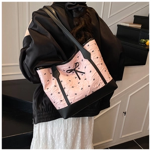 Detail of pink pleated fabric tote bag featuring black bow patterns and leather strap