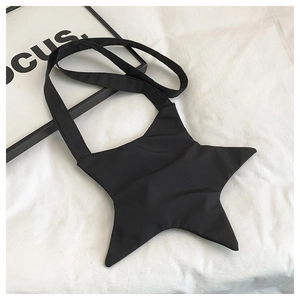 Detailed view of black star-shaped crossbody bag on a textured white fabric backdrop