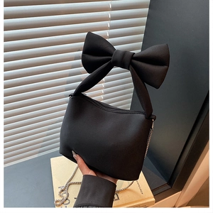 Detail of black bow handbag with matte texture fabric and detachable silver chain strap