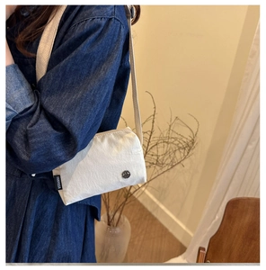 Close-up of white crossbody bag featuring a Fanyissa label and metal logo detail