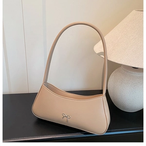 Detail der beige Schultertasche mit silberner Schleifenschnalle und glatter Lederstruktur
