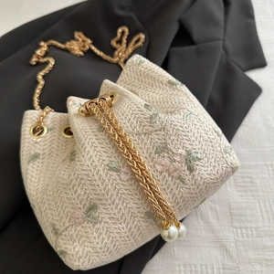 Floral woven straw bucket bag with gold chain strap and pearl drawstring detail