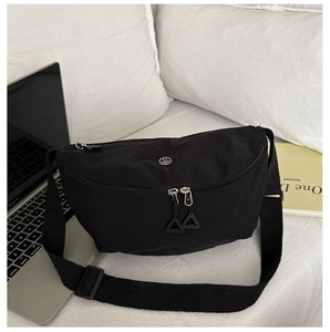 Detail of black nylon crescent crossbody bag with M logo and dual zipper on white fabric
