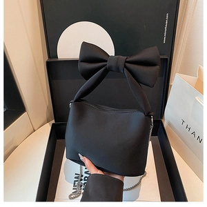 Detail of black bow handbag featuring matte fabric texture and elegant silver chain strap