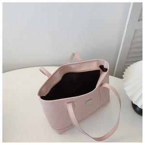 Detail view of pink leather tote bag with embossed cartoon patterns and inner zipper pocket