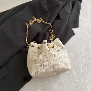 Straw bucket bag with floral embroidery, drawstring closure and gold chain strap