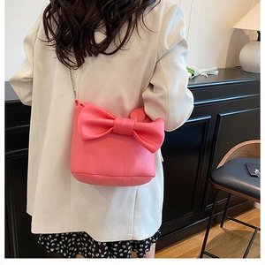 Detailed view of pink bow shoulder bag featuring silver chain strap on white blazer