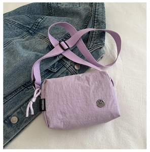 Detail of light purple nylon crossbody bag with textured fabric and metallic brand logo