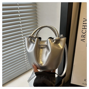 Detailed view of silver glossy bucket bag with drawstring closure and knotted handle