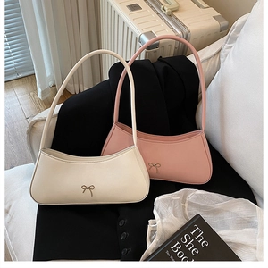 Close-up of elegant underarm bags with gold bow buckles in cream and dusty pink