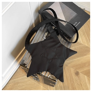 Detail of a black star-shaped crossbody bag hanging on a silver metal suitcase