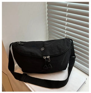 Detail of black nylon crescent bag featuring dual zippers and round metallic logo