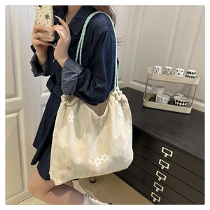 Detail of white tote bag with daisy embroidery and green plaid shoulder strap texture