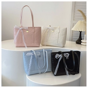 Detail of four pastel tote bags with embossed patterns and delicate lace bow accents