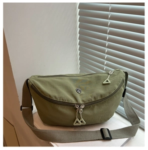 Detail of olive green nylon crescent bag with double zippers and metal logo on strap