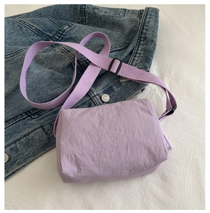 Detail of purple nylon crossbody bag with pleated texture on a blue denim jacket