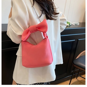 Sac rose à nœud avec bandoulière chaîne argentée porté par un mannequin en blazer