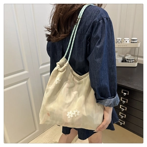 Detail of floral embroidered organza tote bag with woven mint green handles