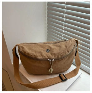 Detailed macro view of a brown nylon crescent bag with a metal letter M logo and dual zippers