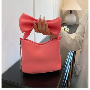 Detailed view of pink bow handle handbag with metallic chain strap and soft velvet texture