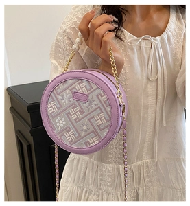 Detail of light purple round bag featuring geometric embroidery and large pearl handle