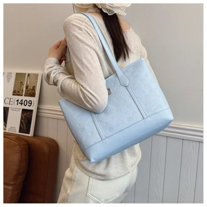 Detail of light blue tote bag featuring embossed cartoon motifs and slim shoulder straps