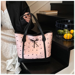 Detail of pink puffy tote bag with black bow patterns and leather handles on stairs
