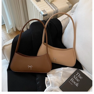 Close-up of minimalist baguette bags with metal bow details in dark brown and beige