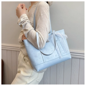 Macro detail of the light blue embossed cartoon pattern and lace bow on the tote bag