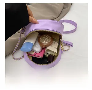 Interior view of small purple round bag showing storage for wallet, lipstick and perfume