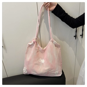 Detail of pink tie-dye tote bag featuring 3D white floral appliqués and thin straps