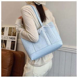 Close-up of light blue tote bag featuring embossed Cinnamoroll design and lace bow detail