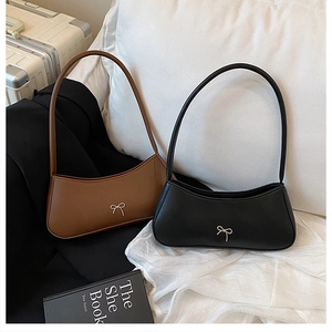 Detail of minimalist leather shoulder bags with metal bow accents in brown and black