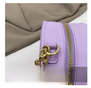 Close-up of premium gold metal chain hooks and smooth zipper on a lilac leather bag