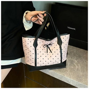 Detail of pink tote bag featuring black heart patterns and a textured wrinkled fabric finish
